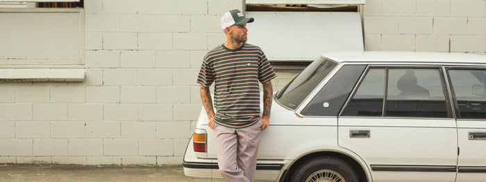 young guy wearing Dickies t-shirt leaning on a white car
